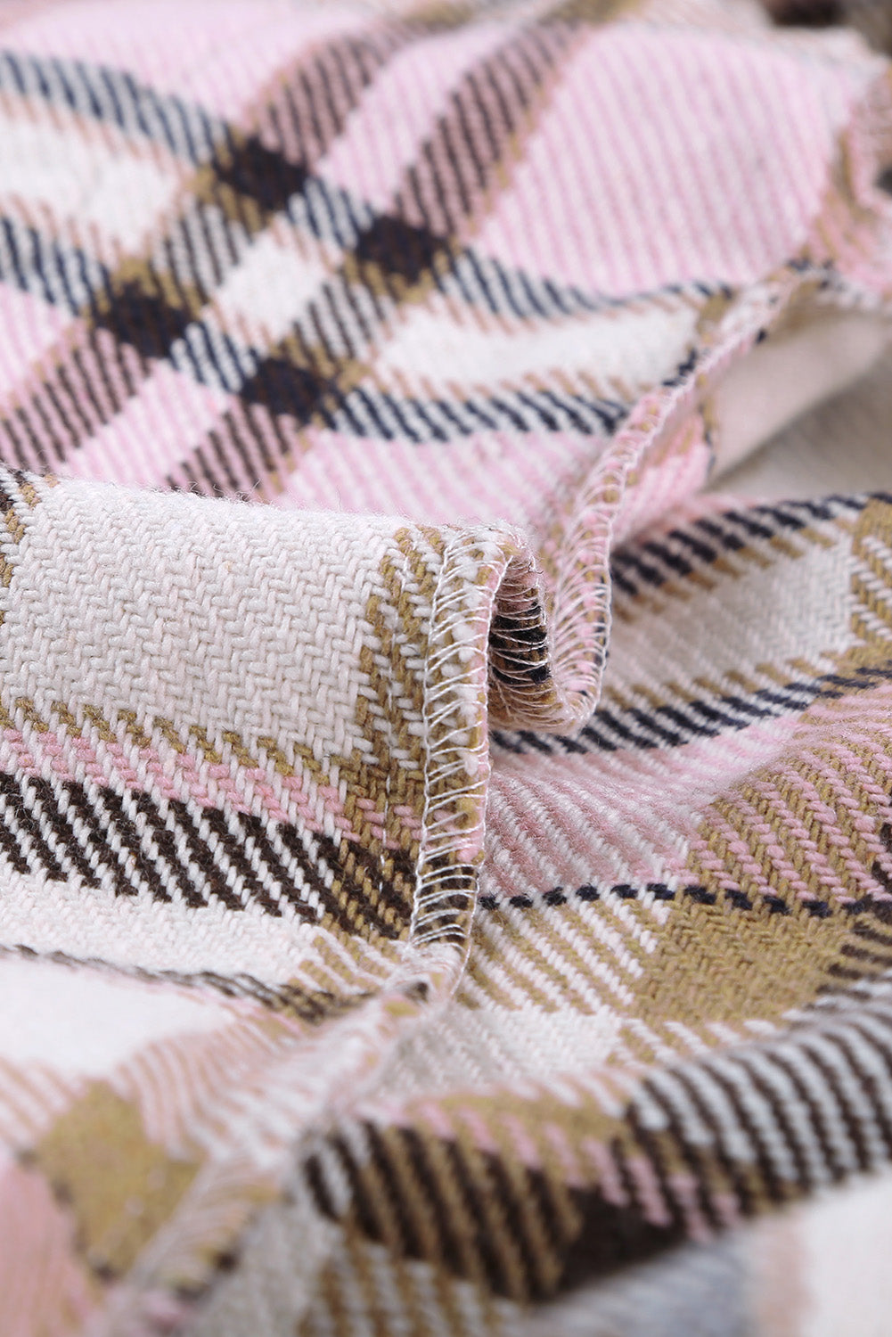 A person wearing a Brown Plaid Button Up Long Sleeve Flannel Shacket layered over a white top with ripped jeans and holding a brown handbag stands against a textured gray wall.