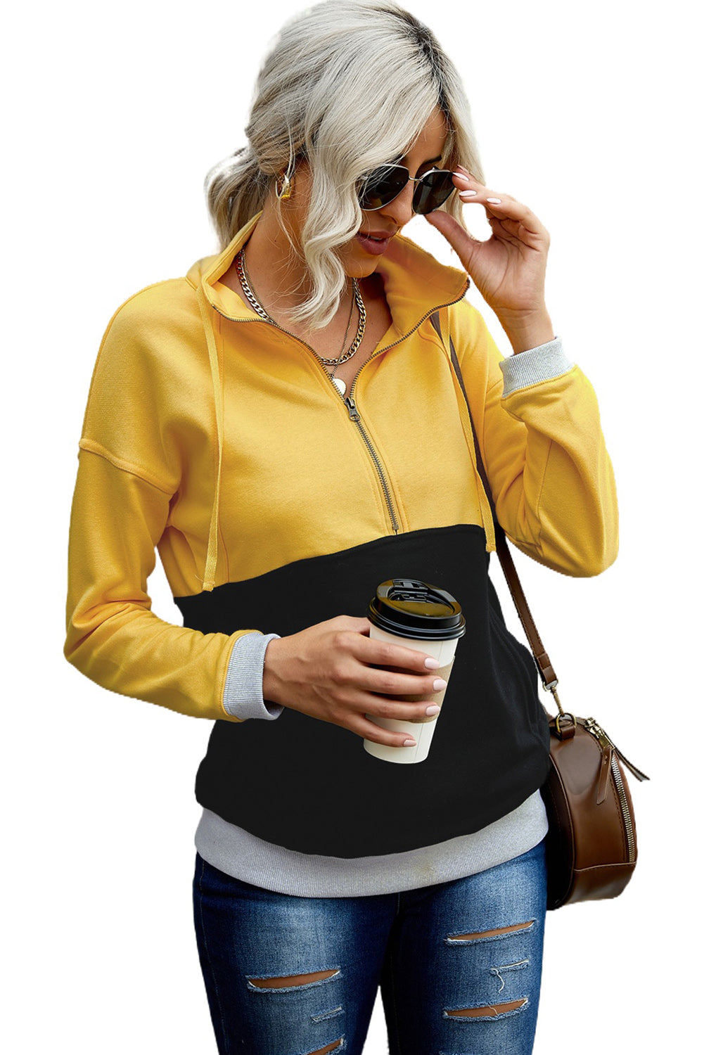 A person with long, light hair in a ponytail, wearing a Black Zipped Colorblock Sweatshirt with Pockets, blue jeans, and glasses, is holding a white cup and a brown handbag, shown from behind against a gray wall.