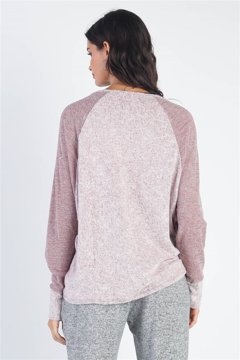 A woman stands wearing the Cherish Apparel Round Neck Long Sleeve Contrast Top in pink and gray with matching gray pants, set against a plain background.