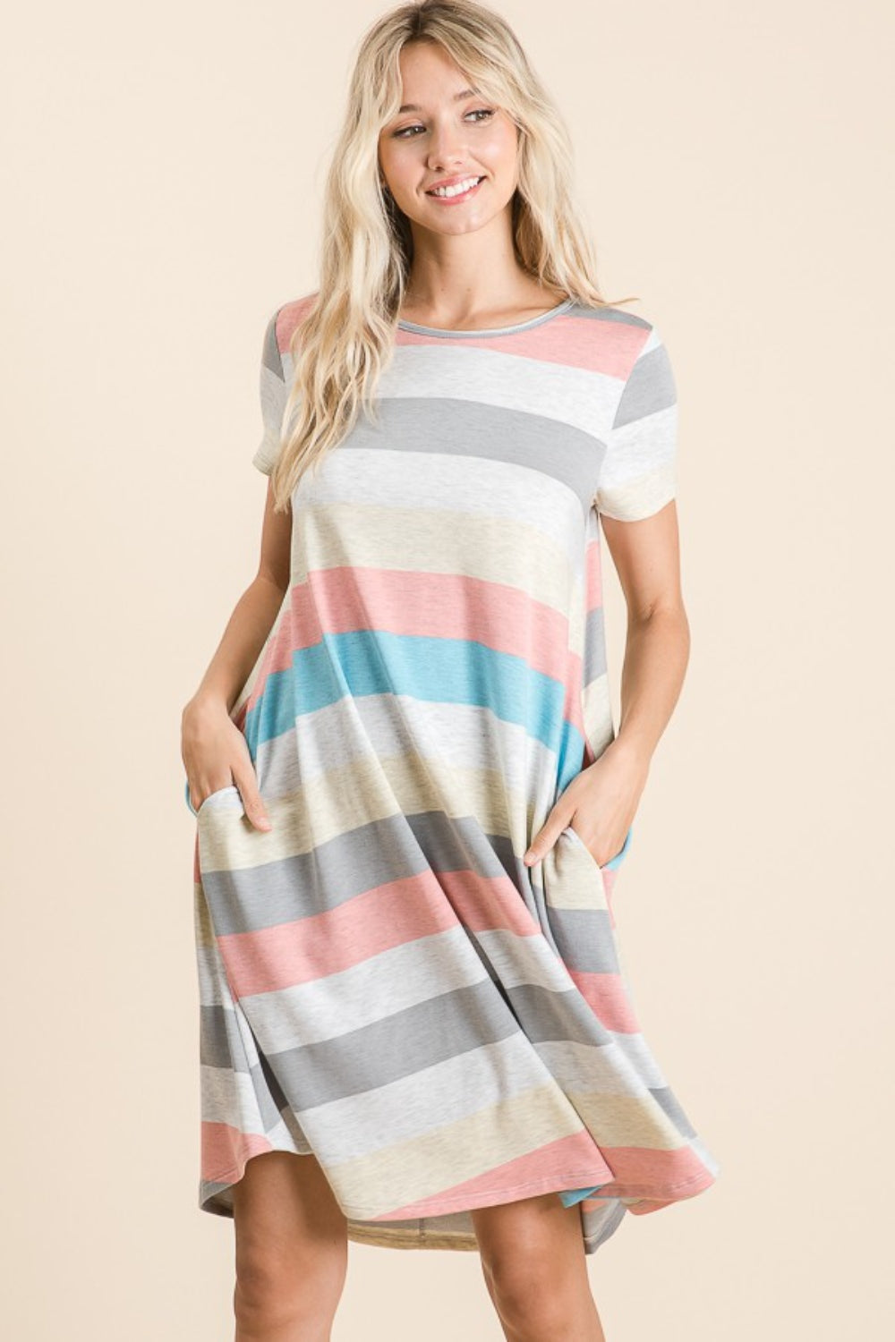 A woman is wearing the BOMBOM Striped Short Sleeve Dress, showcasing multicolored patterns and practical pockets for a casual look.