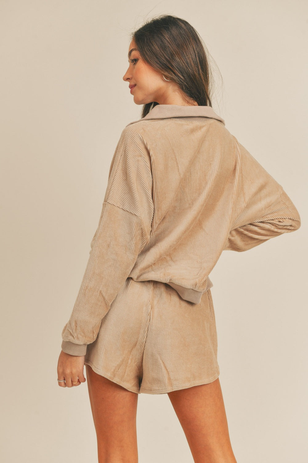 A woman stands confidently, wearing the MABLE Corduroy Half Zip Top and Shorts Set in a matching beige color, with her hands on her hips against a neutral background, effortlessly exuding retro charm.