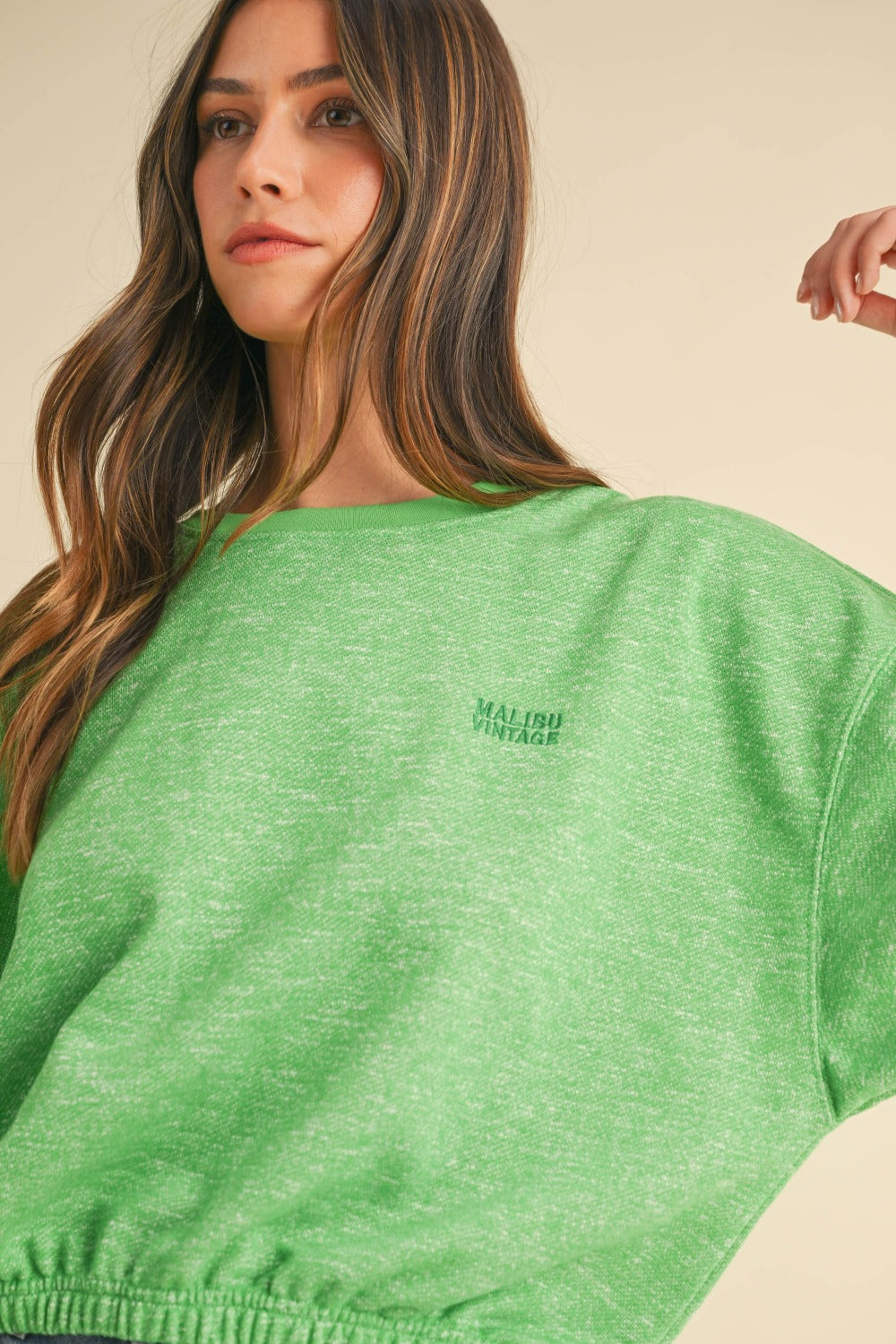 A woman models a Mable Round Neck Letter Embroidery Crop Sweatshirt in green, paired with denim shorts, against a plain background, effortlessly showcasing her street style.