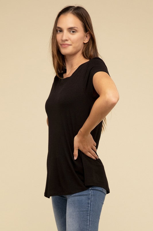 A person with long hair is wearing a blue Flowy Round Hem Rayon Short Sleeve Top and black pants, standing against a plain beige background.