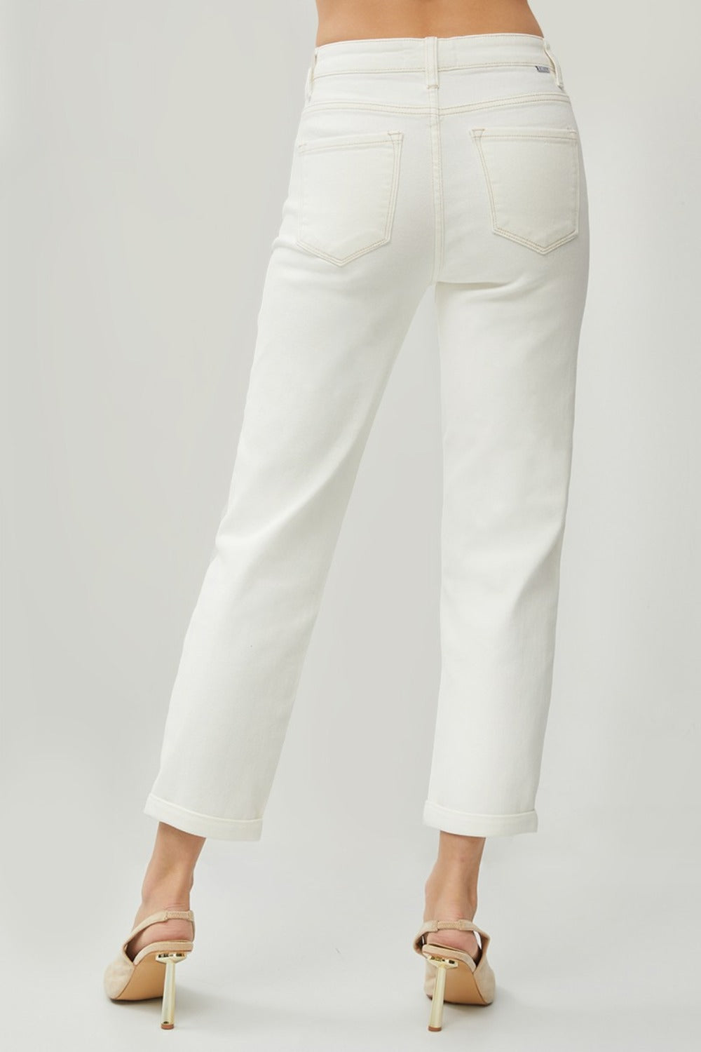 Description: Person wearing RISEN Full Size High Waist Rolled Hem Straight Jeans in white with beige heels against a plain background. 