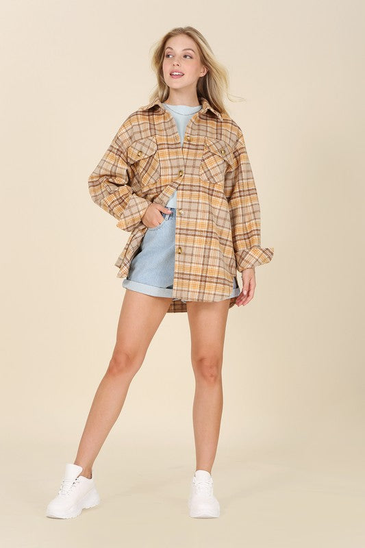 A person wearing the beige and brown Plaid shacket with pockets, featuring long sleeves and large buttons, holds the collar. Blonde hair is visible, adding a touch of elegance to the casual look.