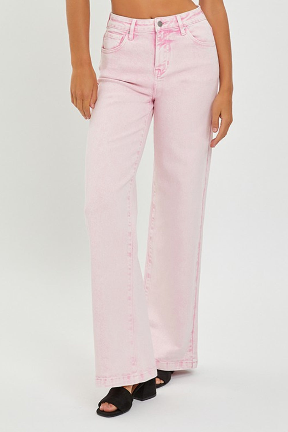 Someone is wearing RISEN Full Size High Rise Tummy Control Wide Leg Jeans in light pink, paired with black heeled sandals against a plain white background.