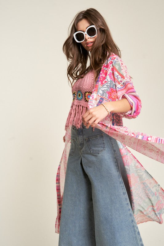 A person wearing round sunglasses and the Mesh Print Mix Matched Button Front Cover Up featuring pink, red, and white tones stands against a plain background over blue jeans.