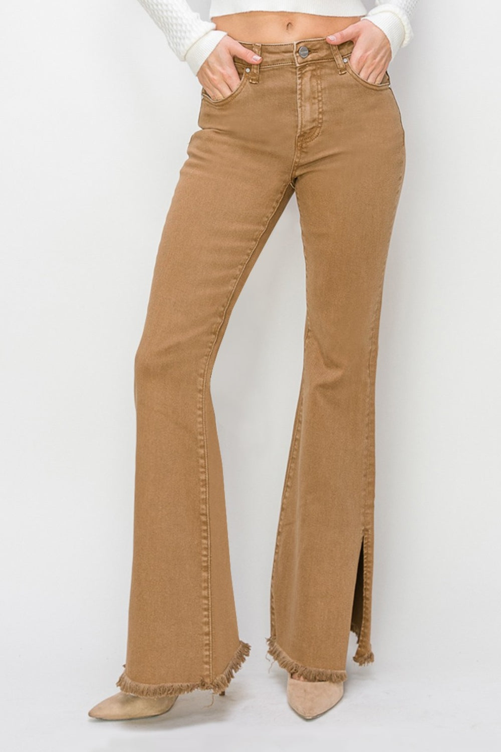 Wearing the RISEN Bailey Full Size High Waist Side Slit Flare Jeans with frayed hems, a person pairs them with beige boots against a white background.