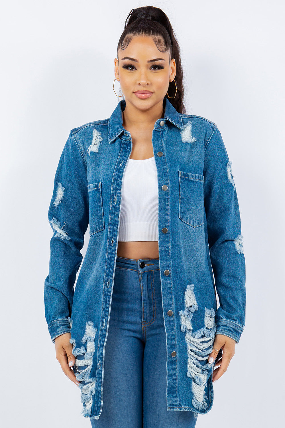 Woman wearing an American Bazi Distressed Button Up Long Sleeve Denim Jacket over a white crop top and blue jeans, standing against a plain background.