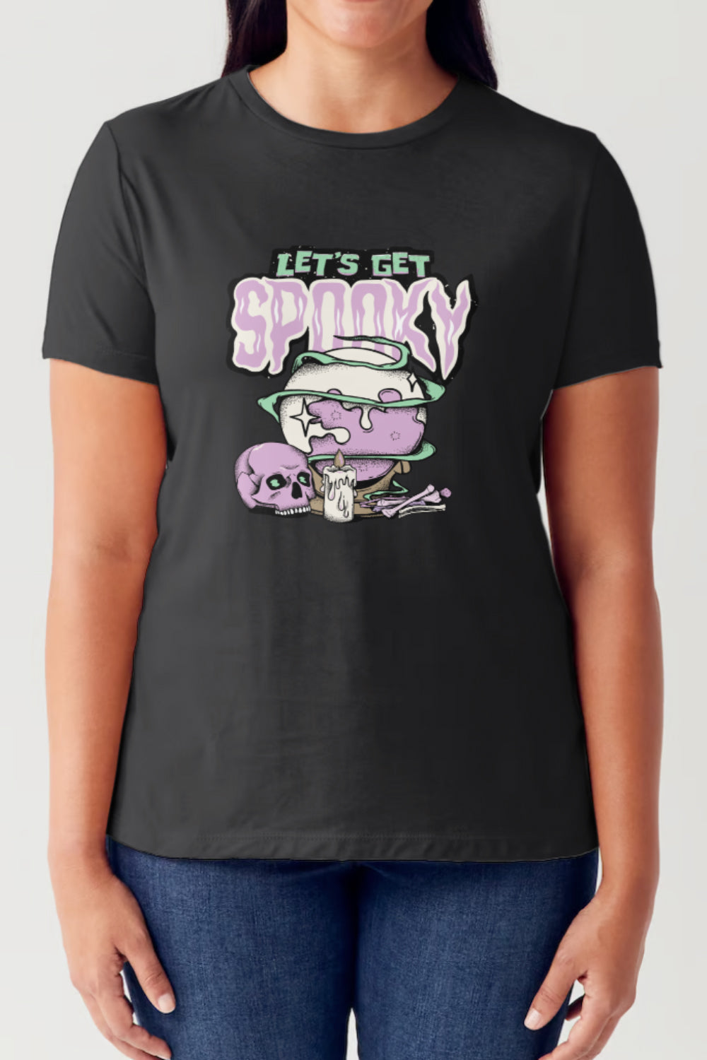 A person wearing the Simply Love Full Size LET'S GET SPOOKY Short Sleeve Tubular T-Shirt, featuring a white color with a graphic of a purple skull, a cauldron, and the text "LET'S GET SPOOKY." Perfect for festive gatherings!