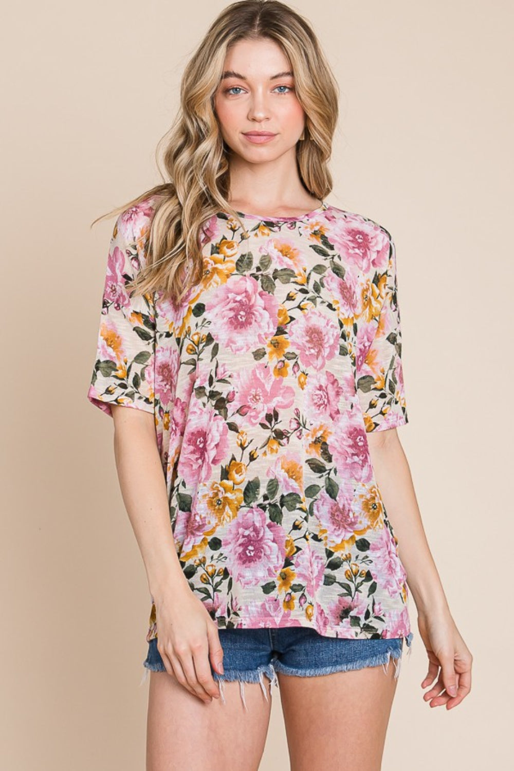 Wearing the BOMBOM Floral Round Neck T-Shirt and denim shorts, a person effortlessly embodies casual elegance against a plain beige background.