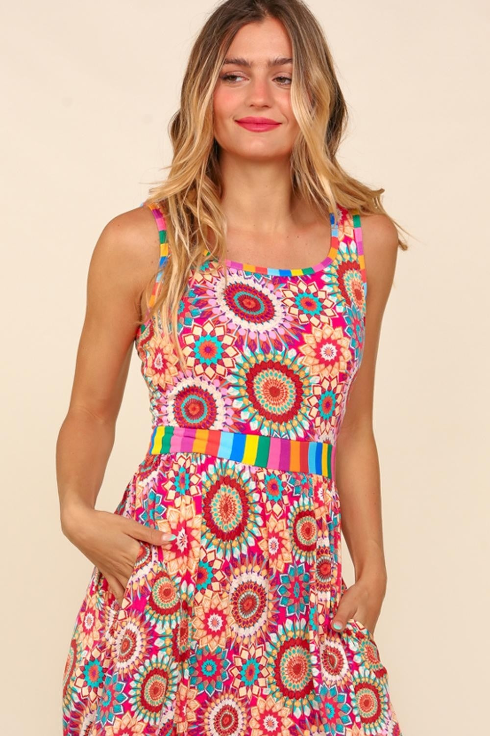 A woman in a vibrant Haptics Full Size Crochet Sleeveless Maxi Dress with side pockets stands and smiles against a plain background, ready for the summer soiree.