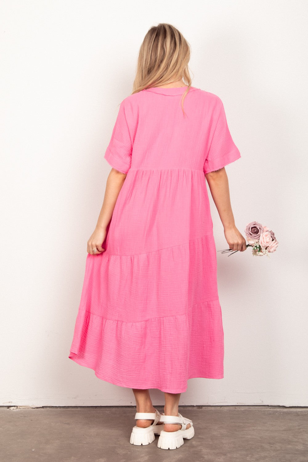 Dressed in the VERY J Soft Crinkle Gauze Short Sleeve Midi Dress in vibrant pink, a person holds a bouquet of flowers, effortlessly capturing summer style against a plain background.