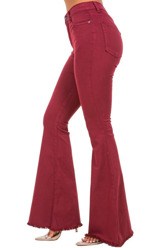 A person wearing high-rise, wine-colored Bell Bottom Jeans with frayed hems (Inseam 32), paired with open-toe shoes.