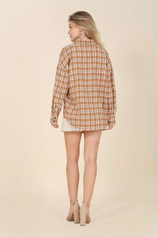 Wearing an Autumn beige plaid shirt, a person with long hair complements their look with hoop earrings, showcasing the season's warm hues. This long-sleeved shirt rests gracefully against a beige backdrop and is ideal for machine wash cold care.