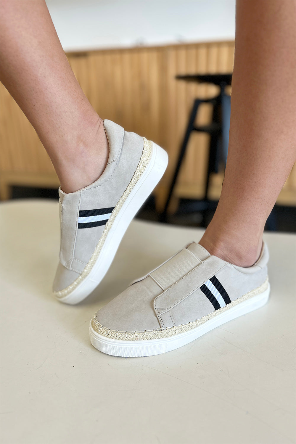 A person wearing the chic CCOCCI Striped Round Neck Sneakers in beige, featuring black and white stripes on a light surface, ideal for everyday wear.