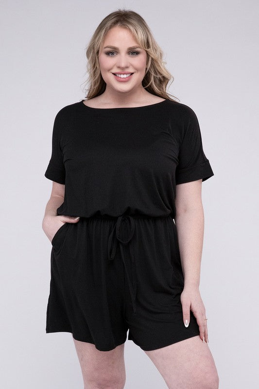 A person is wearing the Plus Brushed DTY Romper with Pockets in bright pink, smiling as they pose with one hand on their head and the other tucked into a pocket, all set against a gray background.