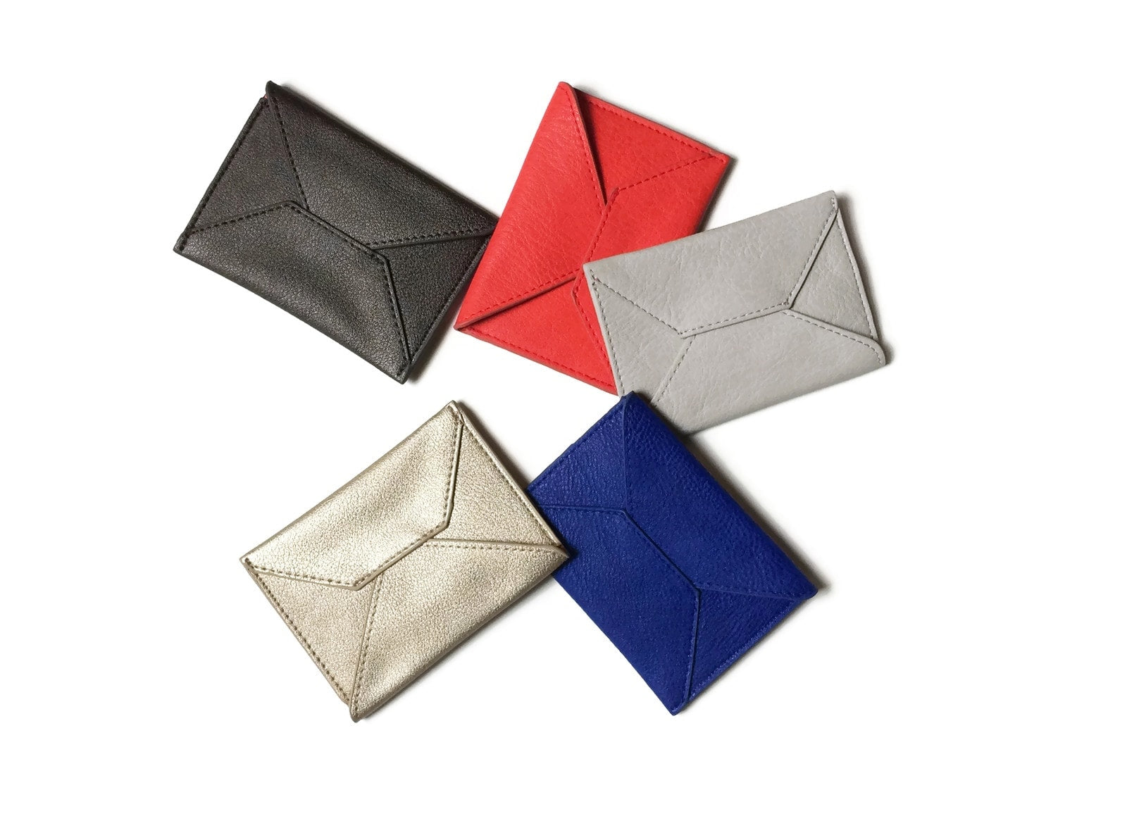 Five Smith Vegan Leather Card Cases in black, red, gray, beige, and blue are elegantly arranged in a circle on a white background. These sleek designs add a sophisticated touch to any occasion.