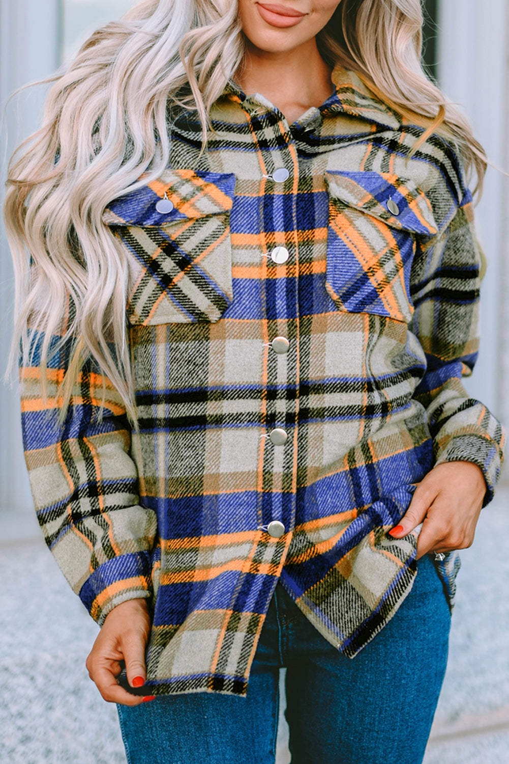 A person wearing a Brown Plaid Button Up Long Sleeve Flannel Shacket layered over a white top with ripped jeans and holding a brown handbag stands against a textured gray wall.