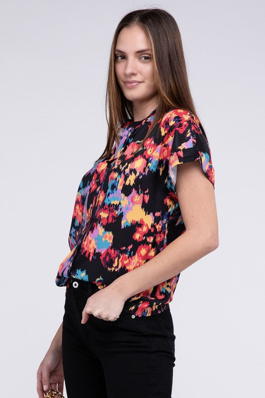 A person stands confidently wearing a colorful, abstract-patterned Notch Neck Top and black pants against a plain background.