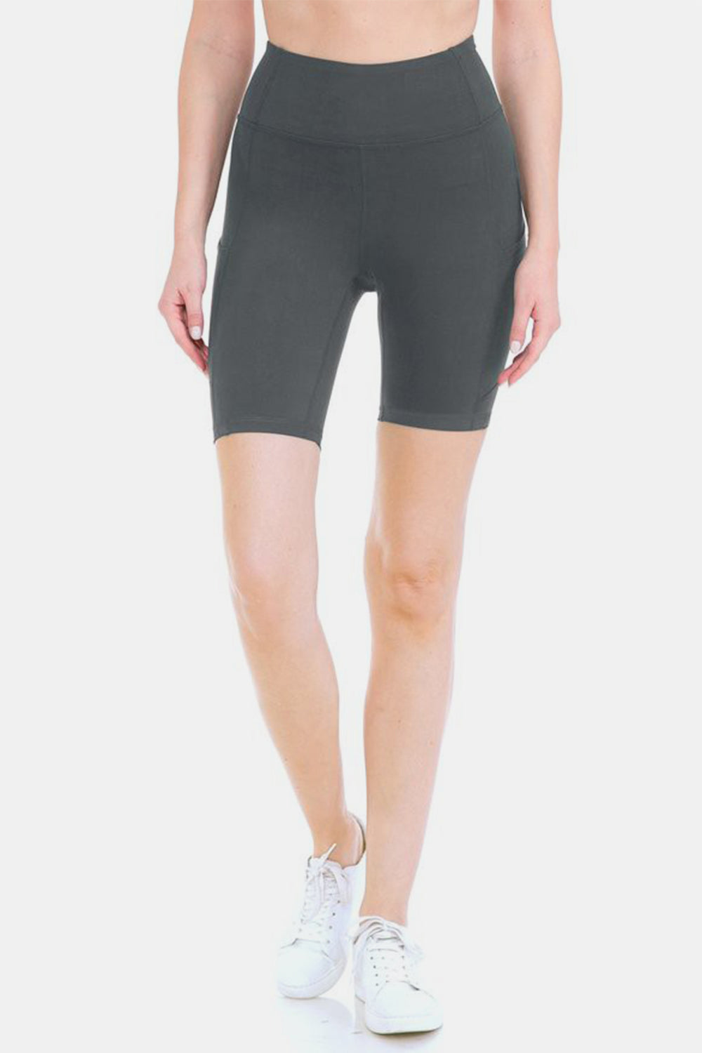 Person placing a smartphone into the side pocket of stylish activewear, featuring Leggings Depot Full Size High Waist Active Shorts made from moisture-wicking fabric.