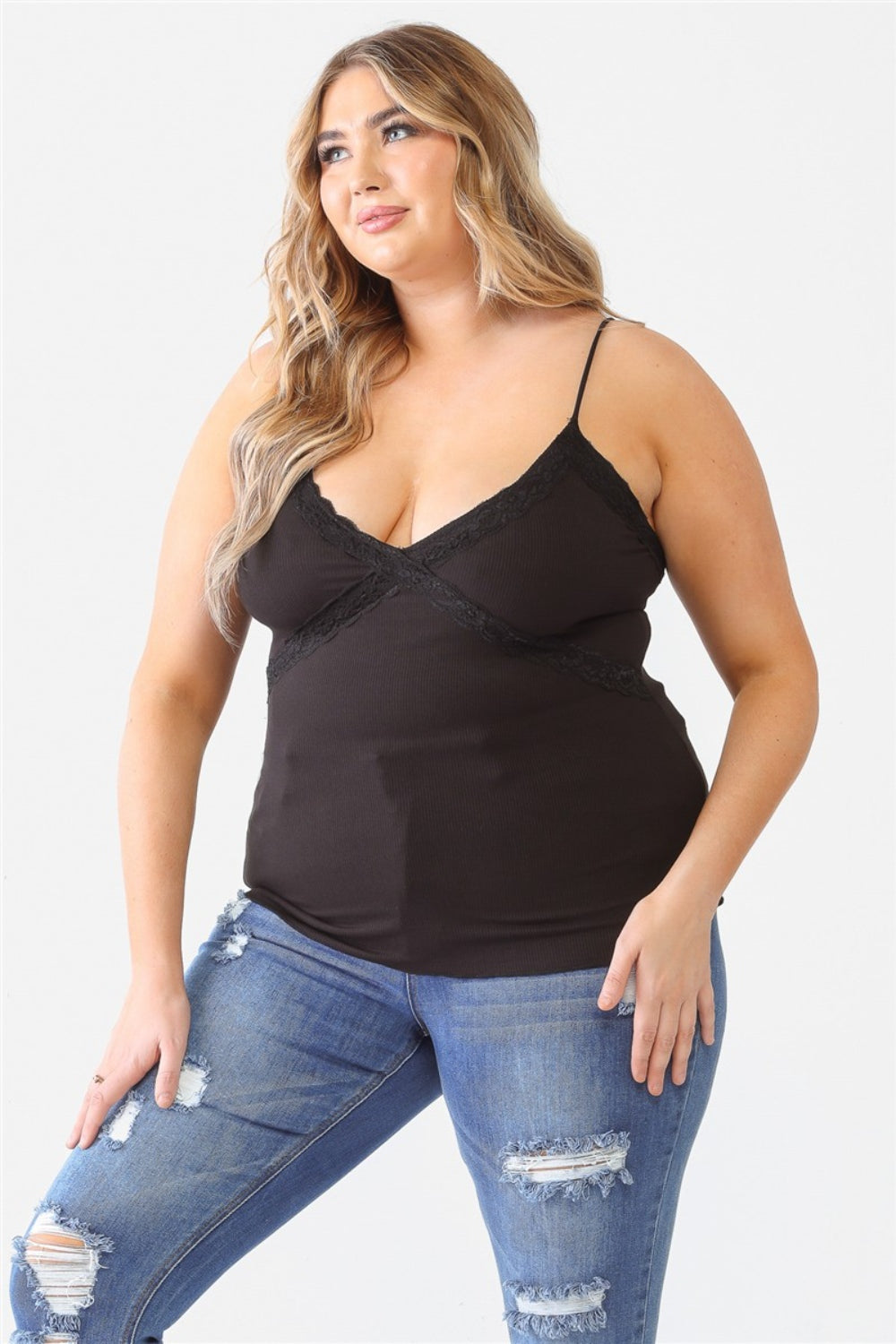 A person with long hair is wearing a Zenobia Plus Size Lace Detail V-Neck Cami and distressed jeans against a plain background.