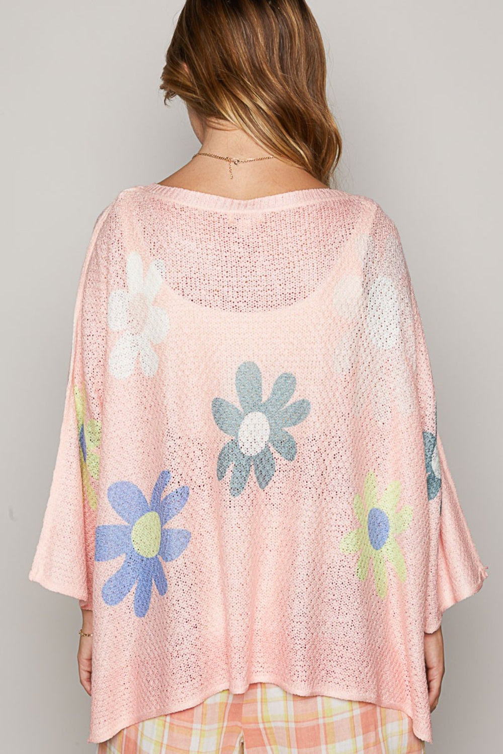 A person is wearing a POL Flower Dropped Shoulder Long Sleeve Knit Top in pink, featuring a large floral pattern, and stands against a neutral background.