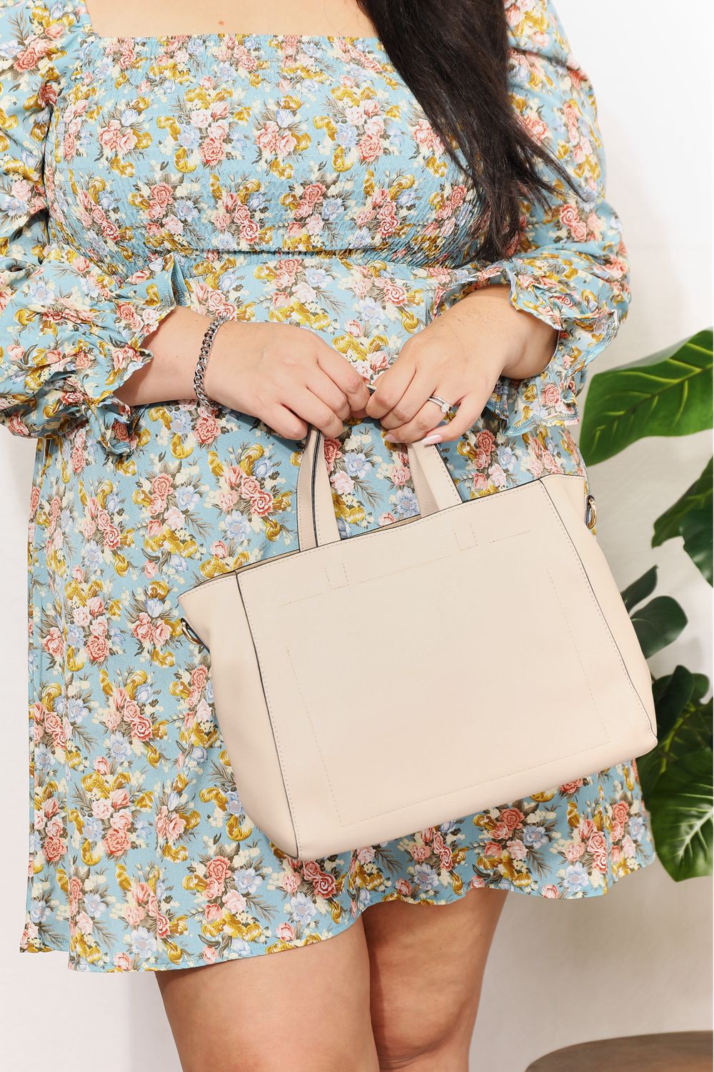 Person wearing a floral dress holds the SHOMICO Medium PU Leather Handbag with both hands.