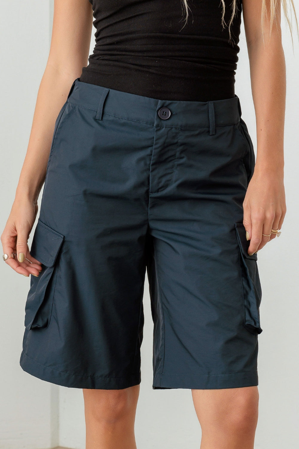 Person wearing a black sleeveless top and Le Lis Navy Cargo Bermuda Shorts with pockets, perfect for a warm-weather wardrobe.