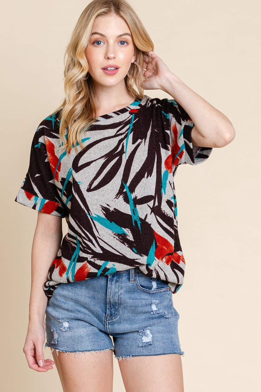 Modeling confidently against a beige background, a person showcases the BOMBOM Printed Round Neck Short Sleeve T-Shirt paired with ripped denim shorts.