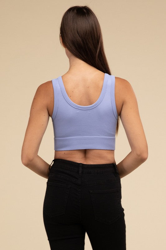 A person with long brown hair wearing the Ribbed Seamless Crop Top in light blue and black pants stands against a beige background, showcasing a perfect summer essential.