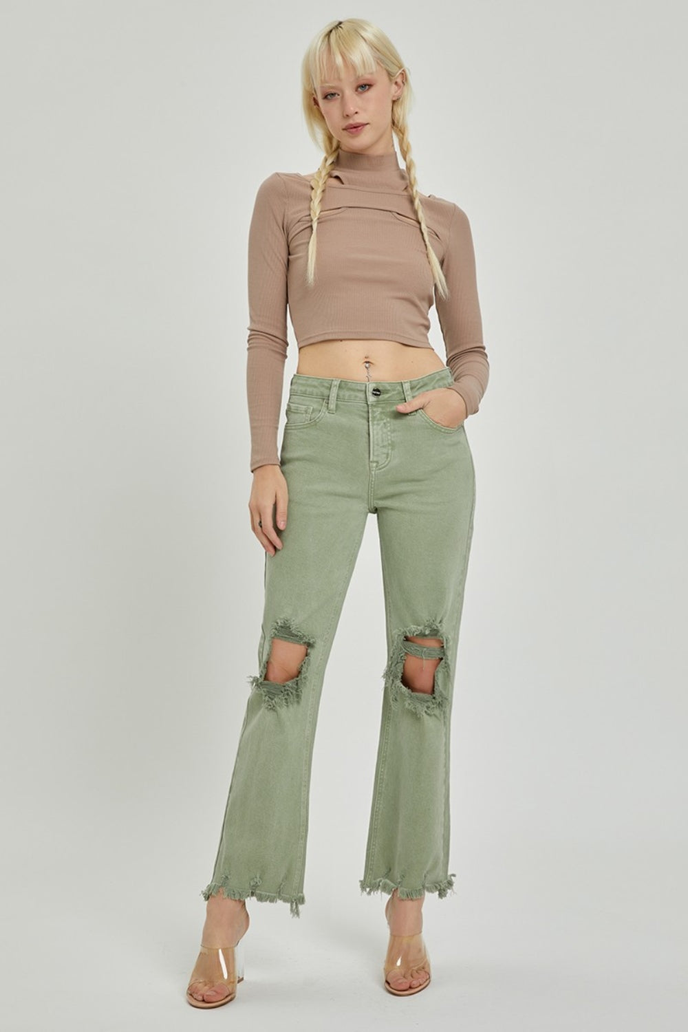 A person wearing RISEN light green distressed ankle bootcut jeans with frayed hems and a beige long-sleeved top, shown from midsection to feet.