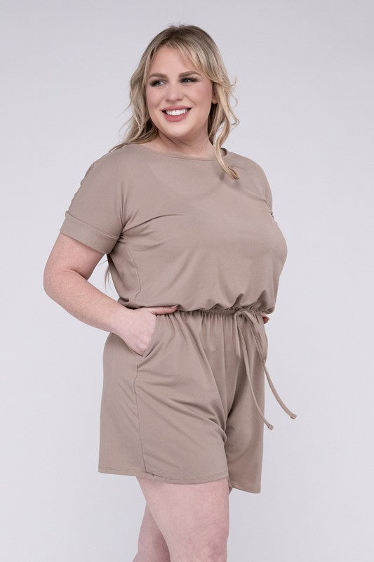 A person is wearing the Plus Brushed DTY Romper with Pockets in bright pink, smiling as they pose with one hand on their head and the other tucked into a pocket, all set against a gray background.