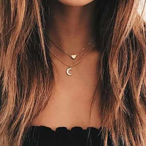 Close-up of a person with long, wavy brown hair wearing the Moon and Heart Two Layer Necklace featuring a heart pendant and crystal crescent moon.