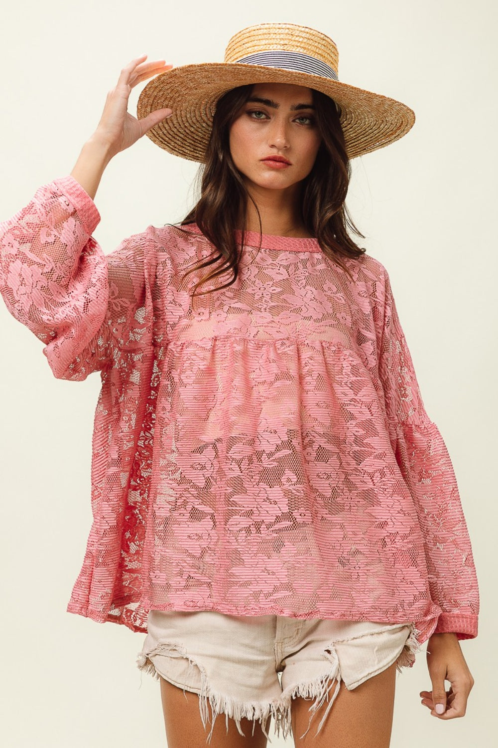 A woman wearing a straw hat, the BiBi Floral Lace Long Sleeve Top, and frayed denim shorts stands against a plain background.