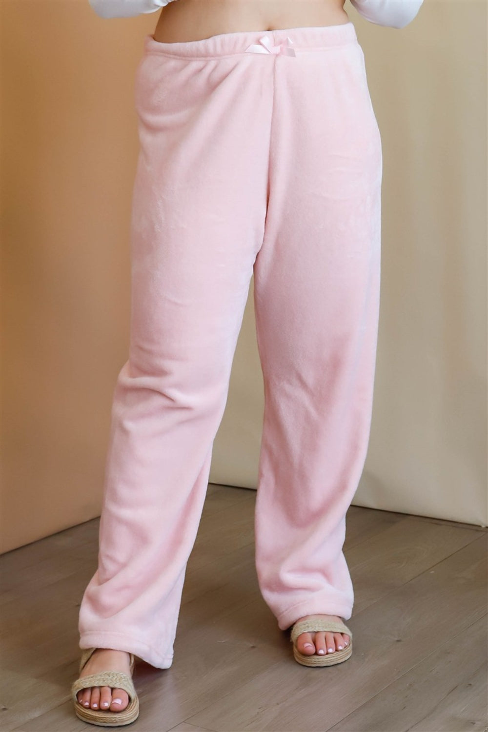 A woman stands in a minimalist room wearing a color-block sweater in beige, white, and light blue, along with Active Usa Plus Size Elastic Waist Wide Leg Pants and beige sandals. She poses with one hand on her hip, embodying a versatile style that combines comfort and elegance.