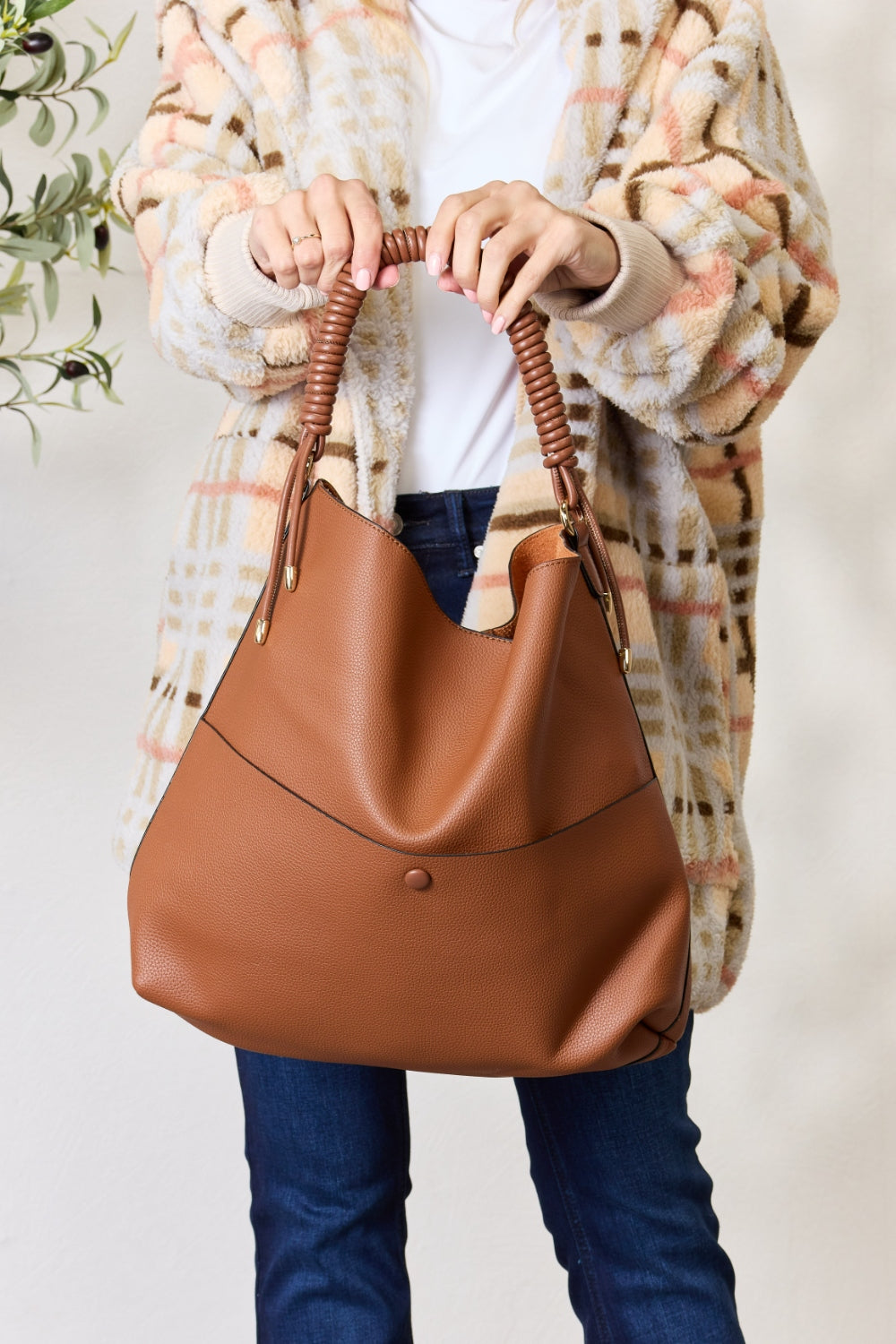 Person carrying a SHOMICO Vegan Leather Handbag with a front pocket and coiled handles, showcasing both versatility and durability.