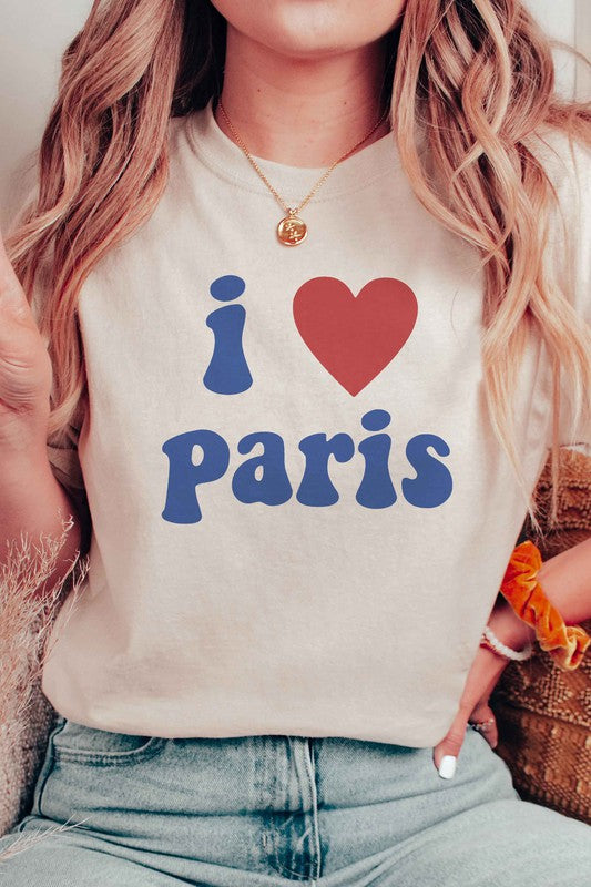 Person wearing a unisex "I LOVE PARIS" graphic tee made from 100% Airlume combed and ringspun cotton, high-waisted denim shorts, and a yellow knit sweater draped over their arms.