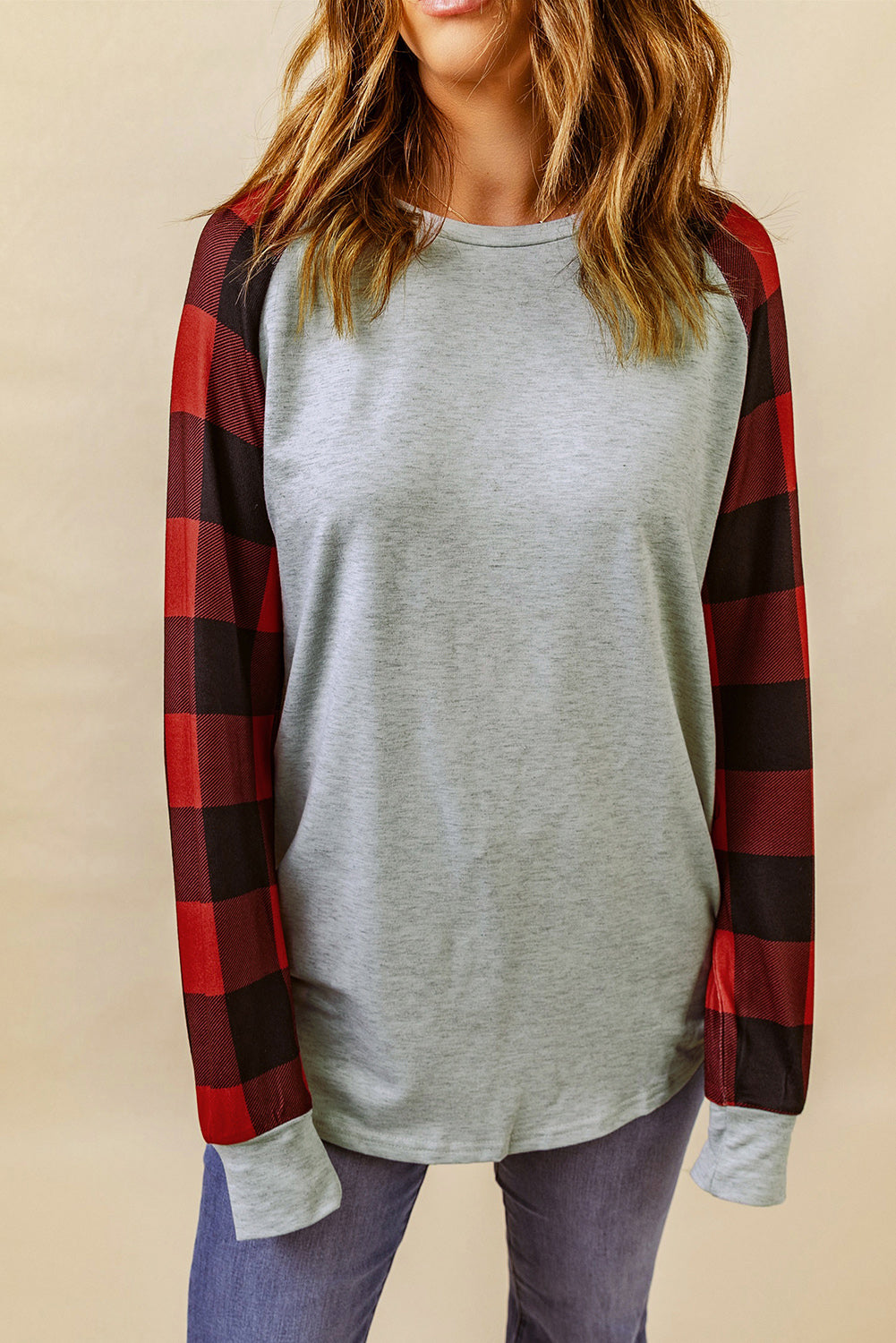 A person with wavy, brown hair is standing with their back to the camera, wearing a Gray Buffalo Plaid Long Sleeve Sweatshirt and blue jeans.