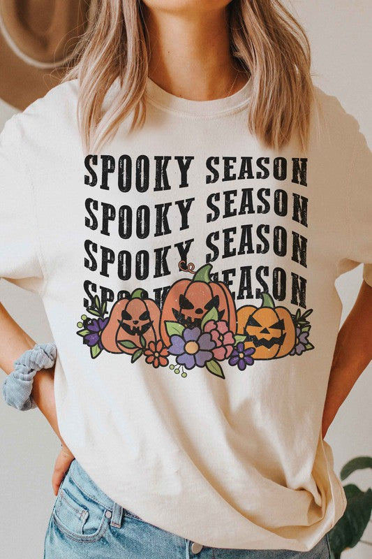 A person is wearing the SPOOKY SEASON PUMPKINS Graphic Tee, featuring "Spooky Season" text and pumpkin graphics, standing with hands by their sides. The unisex sizing ensures a comfortable fit for everyone.