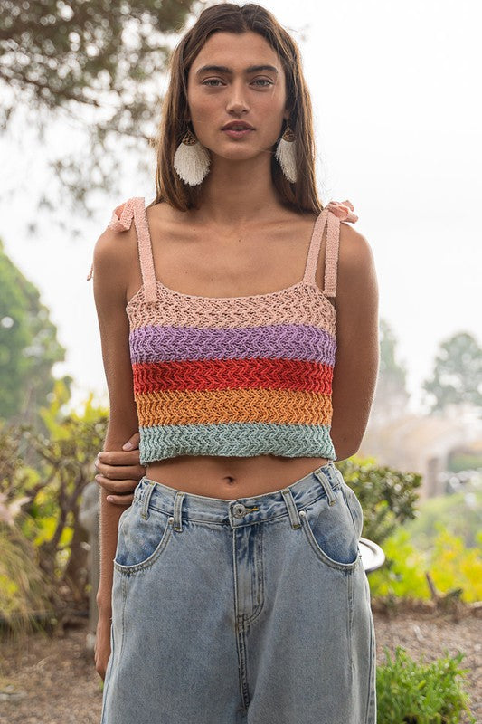 A person is wearing a colorful, rainbow-striped Tie-shoulder Sweater Crop Tank Top paired with light pink pants against a plain background.