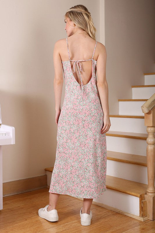 A woman wearing the SL summer dress and white sneakers stands by a staircase next to a white piano.