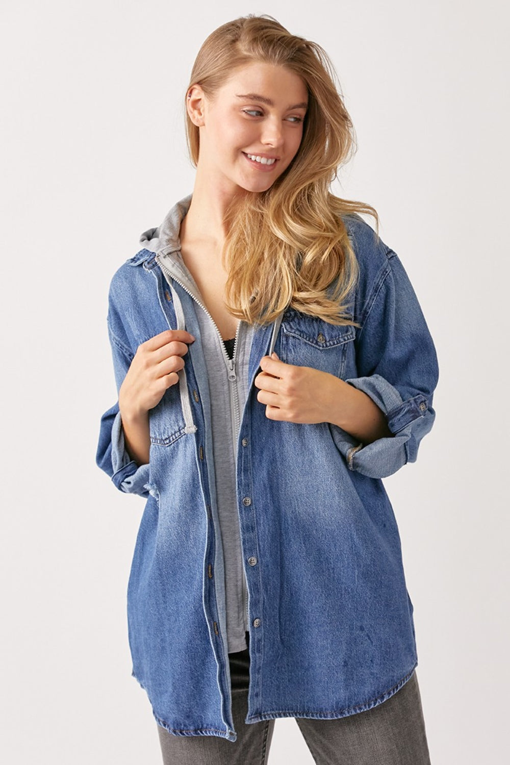 A person with long hair wears a casual oversized grey hooded sweatshirt under a RISEN Zip Up Hooded Denim Shirt.