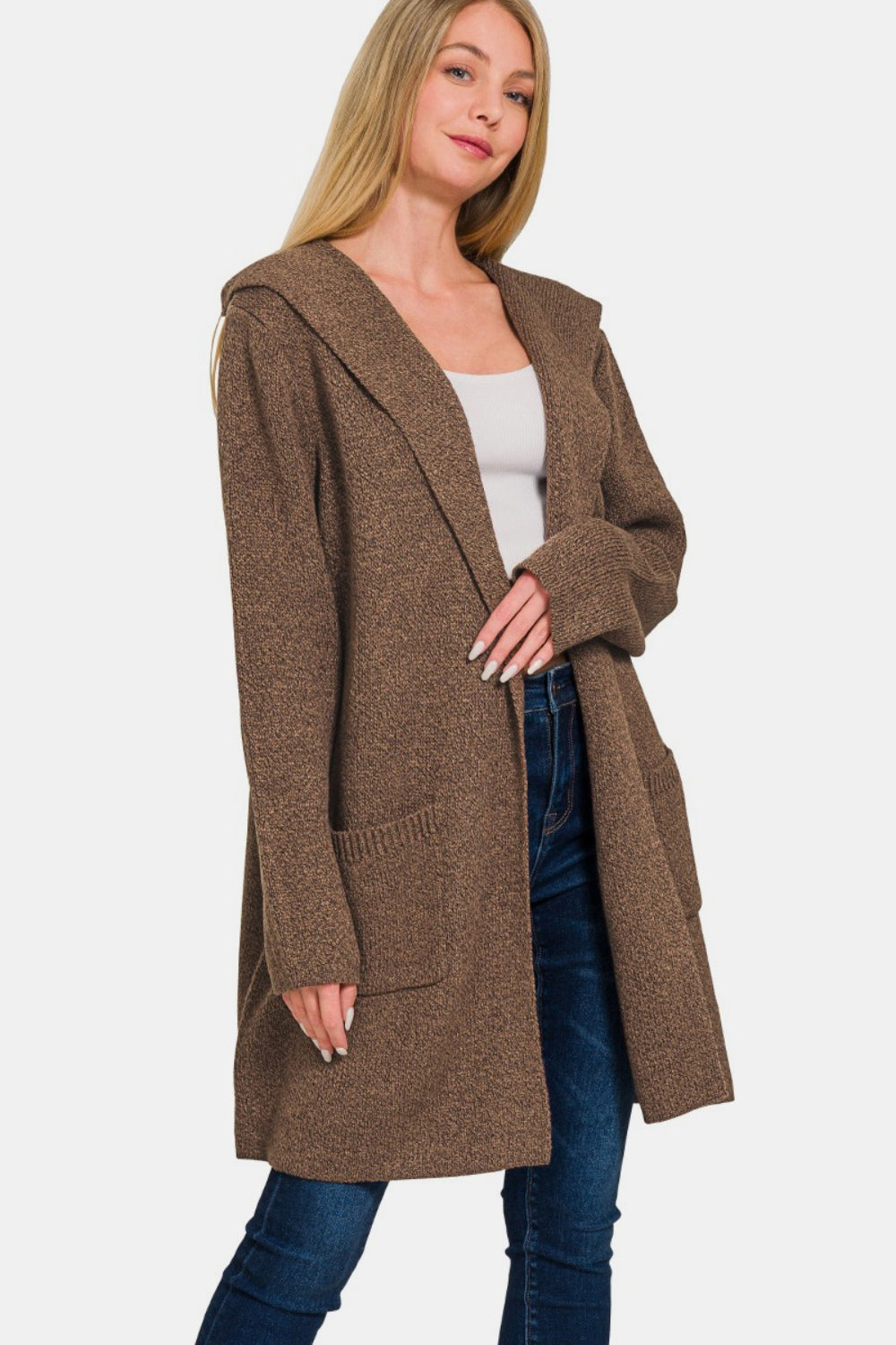 A person wearing a cozy layering piece—a Zenana Hooded Open Front Sweater Cardigan in brown over a white top and jeans—stands against a plain background.