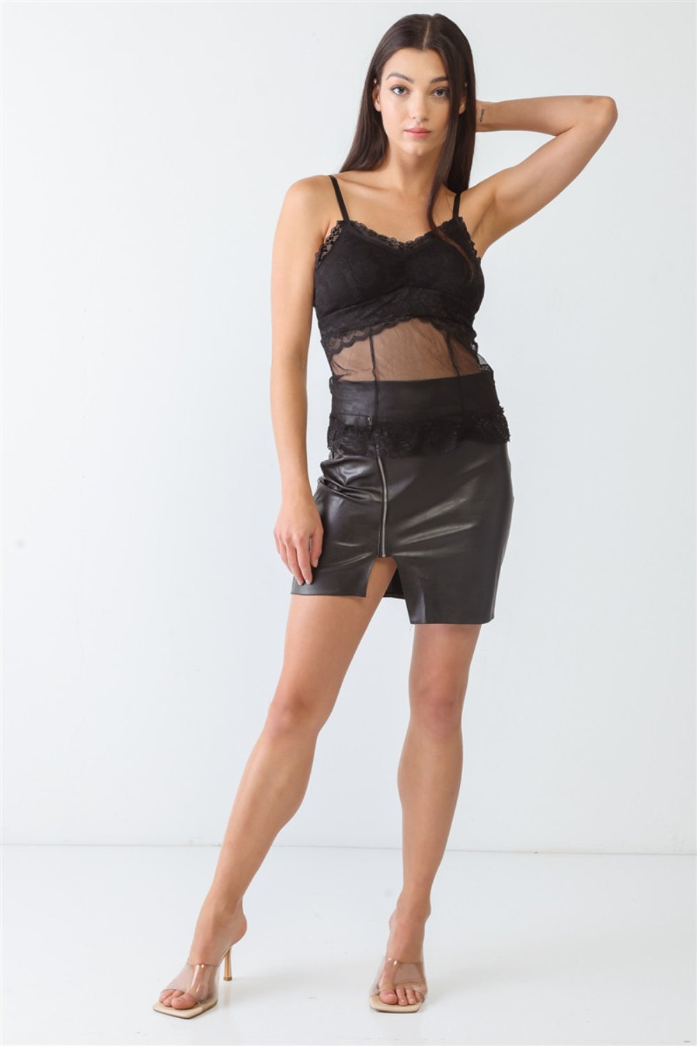 A woman stands wearing a FASHION4YOU Sheer Mesh Lace Push-Up Bustier and a black leather skirt with a front slit against a plain background.