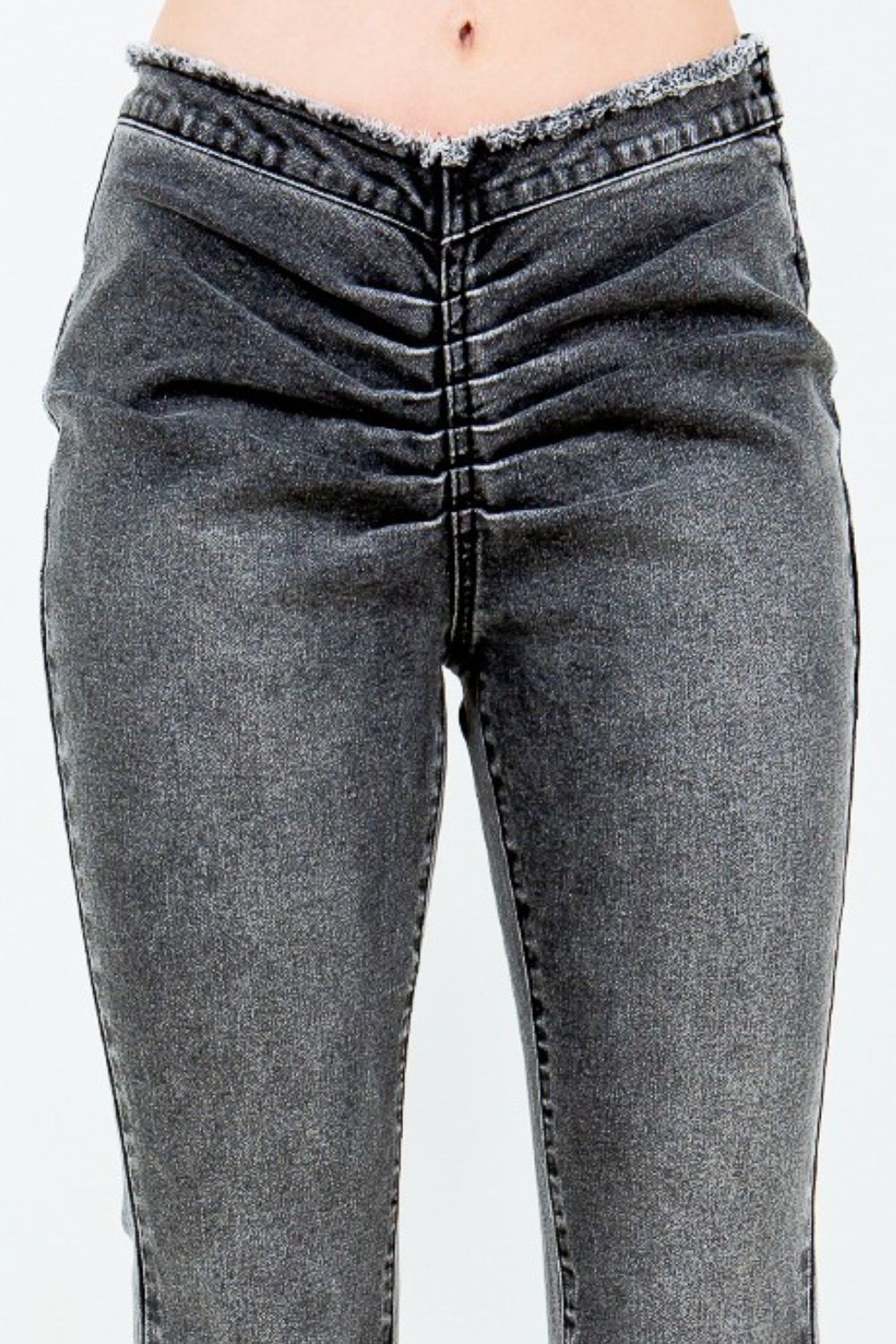 A person wearing American Bazi V-Cut Ruched Flare Pants in gray denim with a high-waisted design and an unfinished hem, standing against a plain background.