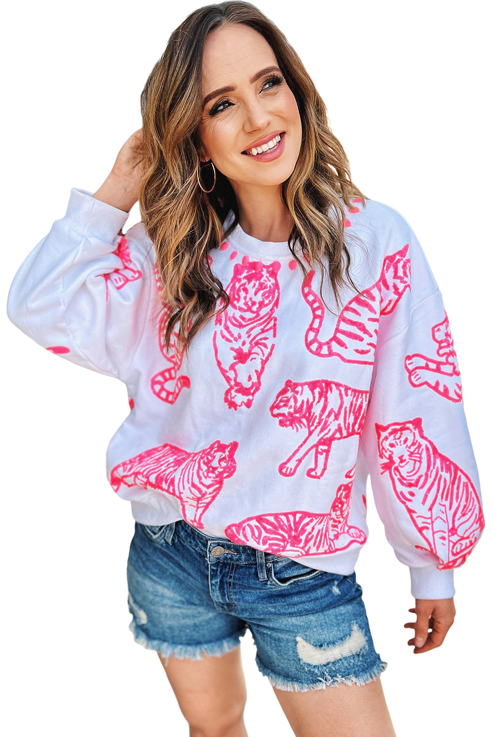 A person with long blonde hair wears a trendy Bright White Pink Animal Print Pullover Sweatshirt, paired with blue jeans, standing outdoors with their back facing the camera.