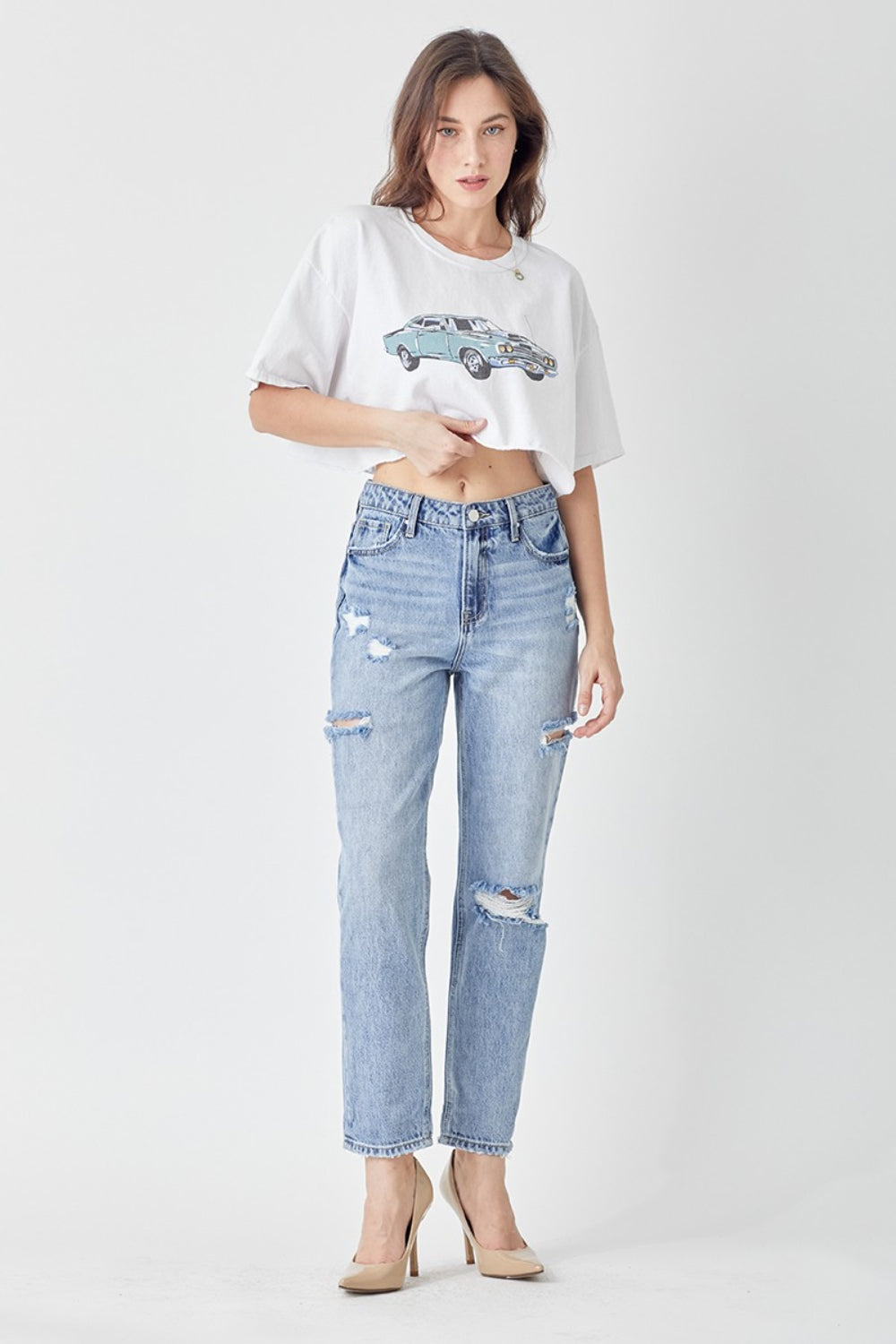 Person wearing the RISEN Distressed Slim Cropped Jeans and beige high heels stands against a plain white background.