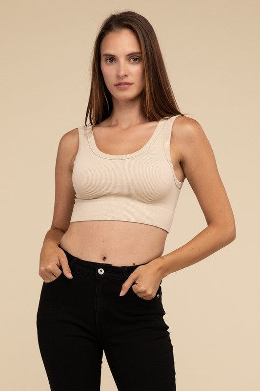 A person with long brown hair wearing the Ribbed Seamless Crop Top in light blue and black pants stands against a beige background, showcasing a perfect summer essential.