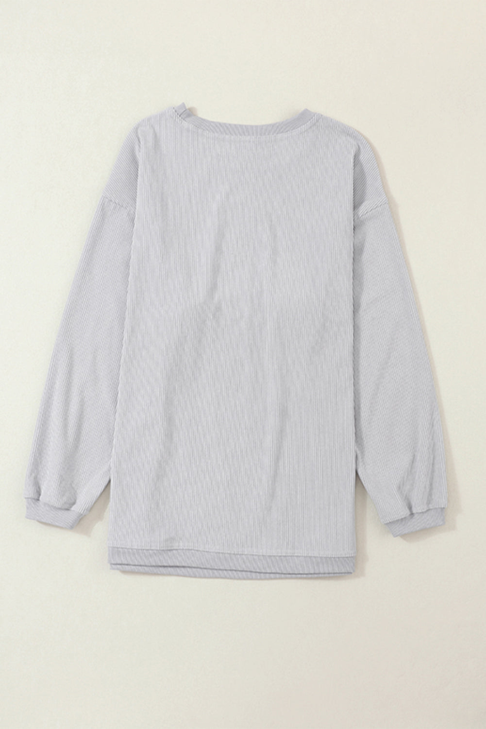 A woman wearing the Light Grey Ribbed Corduroy Oversized Sweatshirt with loose long sleeves, designed in corded fabric, making it fashionable for all body shapes.